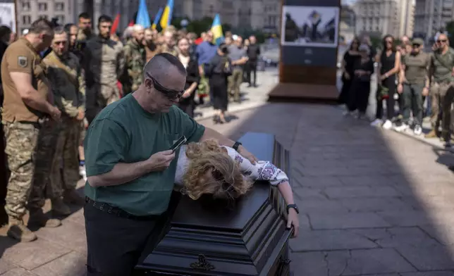 Partner of British combat medic, volunteer, Peter Fouche, 49 who was killed on June 27 during his work in East Ukraine, mourns during the funeral ceremony on the city's main square in Kyiv, Ukraine, Saturday, July 6, 2024. Peter was founder of a charity organization, which provides vehicles, drones and other needs to Ukrainian servicemen. (AP Photo/Alex Babenko)