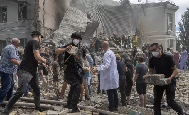 Rescuers, volunteers and medical workers clean up the rubble and search victims after Russian missile hit the country's main children hospital Okhmadit during massive missile attack on many Ukrainian cities in Kyiv, Ukraine, Monday, July 8, 2024. A major Russian missile attack across Ukraine killed at least 20 people and injured more than 50 on Monday, officials said, with one missile striking a large children’s hospital in the capital, Kyiv, where emergency crews searched rubble for casualties. (AP Photo/Efrem Lukatsky)