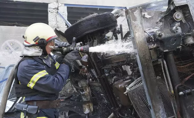 A rescue worker extinguishes a truck on fire which was destroyed by a Russian attack on Nova Poshta delivery, in Kharkiv, Ukraine, Sunday, June 30, 2024. At least one person was killed and several injured. (AP Photo/Andrii Marienko)