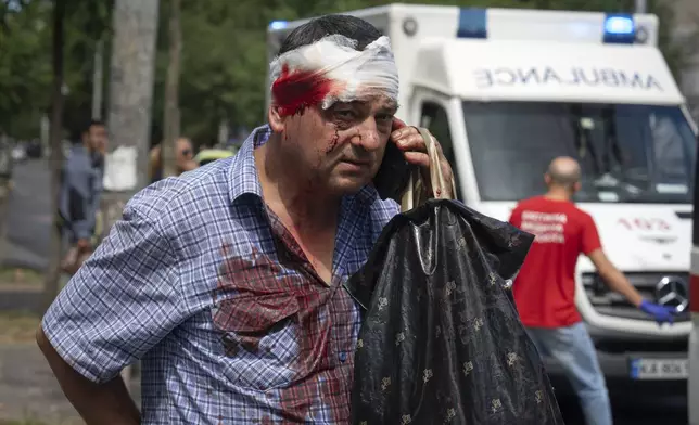 An injured man talks on the phone after Russia's missile attack in Kyiv, Ukraine, Monday, July 8, 2024. A major Russian missile attack across Ukraine killed at least 20 people and injured more than 50 on Monday, officials said, with one missile striking a large children’s hospital in the capital, Kyiv, where emergency crews searched rubble for casualties. (AP Photo/Efrem Lukatsky)