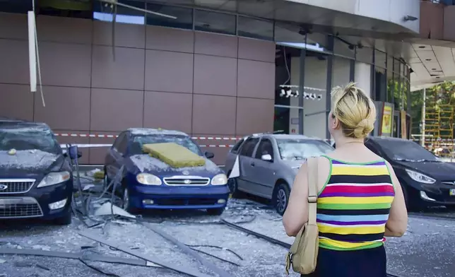 In this photo released by the Dnipro Regional Administration, a woman looks on damaged cars after Russia's missile attack in Dnipro, Ukraine, Wednesday, July 3, 2024. (Dnipro Regional Administration via AP)