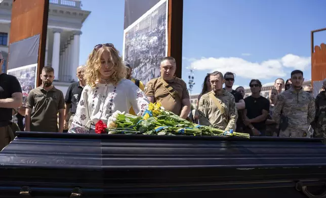 Partner of British combat medic, volunteer, Peter Fouche, 49 who was killed on June 27 during his work in East Ukraine, stands at the coffin during the funeral ceremony on the city's main square in Kyiv, Ukraine, Saturday, July 6, 2024. Peter was founder of charity organization, which provides vehicles, drones and other needs to Ukrainian servicemen. (AP Photo/Alex Babenko)