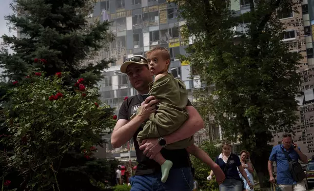 A child is carried near the site of Okhmatdyt children’s hospital hit by Russian missiles, in Kyiv, Ukraine, Monday, July 8, 2024. Russian missiles have killed several people and struck a children’s hospital in the Ukrainian capital, Kyiv, authorities say. (AP Photo/Evgeniy Maloletka)