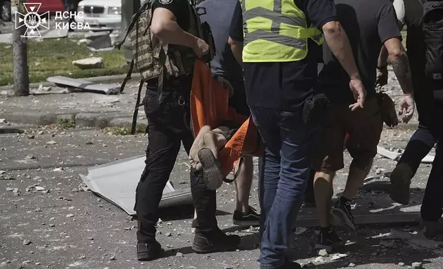 In this photo released by Ukrainian State Emergency Service, rescuers carry a person after a Russia's missile attack in Kyiv, Ukraine, Monday, July 8, 2024. A major Russian missile attack across Ukraine killed at least 20 people and injured more than 50 on Monday, officials said, with one missile striking a large children's hospital in the capital, Kyiv, where emergency crews searched rubble for casualties. (Ukrainian State Emergency Service via AP)