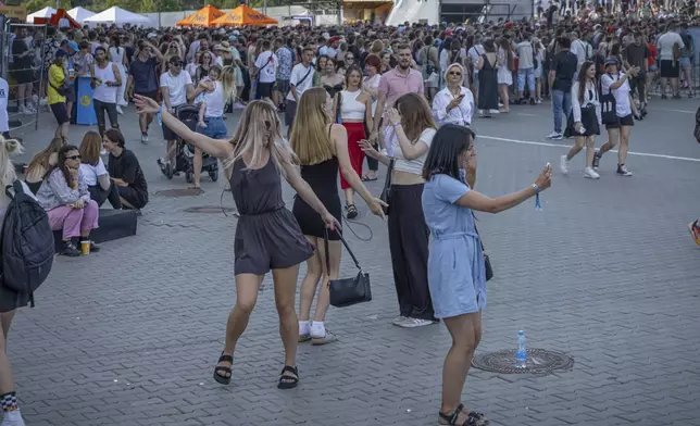 People dance waiting for the start of the Atlas Festival in Kyiv, Ukraine, Sunday, July 21, 2024. This year, Ukraine's largest music festival struck a different chord. Gone were the international headliners, the massive performance halls and the hundreds of thousands of visitors. (AP Photo/Anton Shtuka)