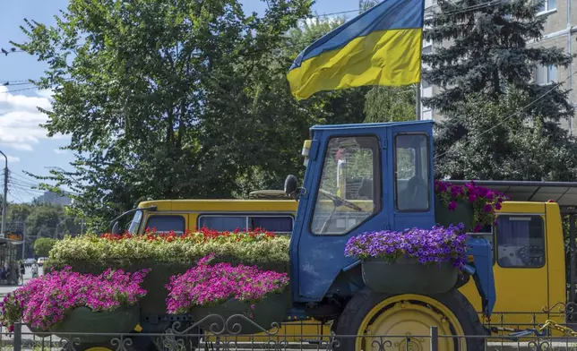A traсtor decorated with flowers and a Ukrainian flag, is seen in Kyiv, Ukraine, Wednesday, June 26, 2024. The tractor symbolises Ukrainian resilience, reminiscent of the early days of the full-scale invasion when ordinary people used tractors to help the military transport abandoned Russian equipment. Despite hardships brought by war flowers fill Kyiv and other Ukrainian cities. (AP Photo/Anton Shtuka)
