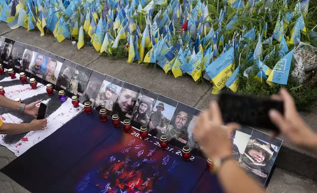 FILE - Photos of Ukrainian POWs killed in the explosions at the Russian-controlled barracks in Olenivka, eastern Ukraine, are placed around a memorial in Kyiv, Ukraine, Saturday, July 29, 2023, to mark the first-year anniversary of the attack. (AP Photo/Jae C. Hong, File)