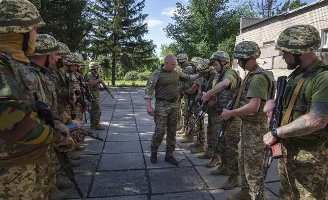 A Ukrainian military instructor of Arey Battalion checks weapons of convict prisoners who have joined the Ukrainian army during training at the polygon, in the Dnipropetrovsk region, Ukraine, Saturday, June 22, 2024. Ukraine is expanding its military recruiting to cope with battlefield shortages more than two years into fighting Russia’s full-scale invasion. (AP Photo/Evgeniy Maloletka)