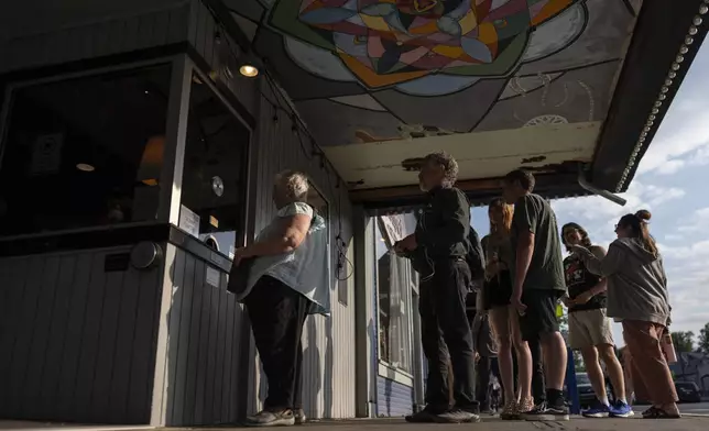 Moviegoers line up to purchase tickets for the 7 p.m. showing of Raising Arizona at the Littel Art Theatre on Thursday, May 16, 2024, in Yellow Springs, Ohio. When the Little Art Theatre set out to land a $100,000 grant to fund a stylish new marquee, the cozy arthouse theater had some talented help. Oscar-winning documentarian Steve Bognar lives in Yellow Springs, the bohemian Ohio town where the theater's a downtown fixture. (AP Photo/Carolyn Kaster)