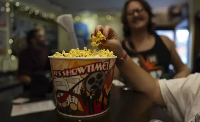 Hot buttered popcorn is tasted before the 7 p.m. showing of Raising Arizona at the Littel Art Theatre on Thursday, May 16, 2024, in Yellow Springs, Ohio. When the Littel Art Theatre set out to land a $100,000 grant to fund a stylish new marquee, with a nod to its century-long history, the cozy Ohio arthouse theater had some talented help. Academy Award-winning documentary filmmaker Steve Bognar is a resident of Yellow Springs,where the theater is a downtown fixture. Besides being one of Little Art’s biggest fans, Bognar is an advocate for small independent theaters everywhere, as they struggle to survive in an industry now dominated by home streaming. (AP Photo/Carolyn Kaster)