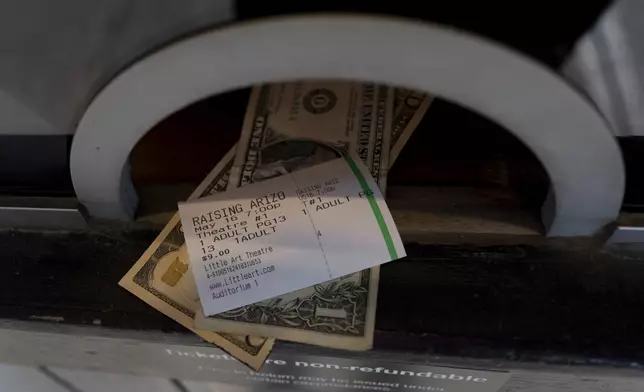 A ticket and change for the 7 p.m. showing of Raising Arizona is handed out of the ticket booth at the Littel Art Theatre on Thursday, May 16, 2024, in Yellow Springs, Ohio. When the Little Art Theatre set out to land a $100,000 grant to fund a stylish new marquee, the cozy arthouse theater had some talented help. Oscar-winning documentarian Steve Bognar lives in Yellow Springs, the bohemian Ohio town where the theater's a downtown fixture. (AP Photo/Carolyn Kaster)