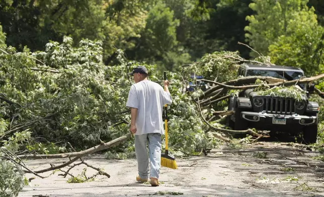 Resident Daniel Ortiz helps clear downed trees along West Huron Street in Chicago's West Town neighborhood, Tuesday, July 16, 2024, after severe storms passed through the Chicago area the night before. (Pat Nabong/Chicago Sun-Times via AP)