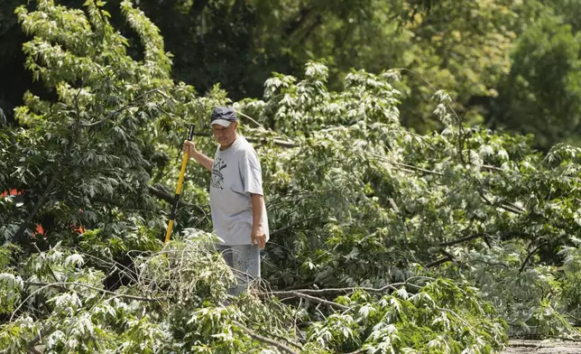 Resident Daniel Ortiz helps clear downed trees along West Huron Street in Chicago's West Town neighborhood, Tuesday, July 16, 2024, after severe storms passed through the Chicago area the night before. (Pat Nabong/Chicago Sun-Times via AP)