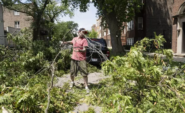 Roger O'Hearnahan helps clear a tree from a road near West Huron and North Leavitt street in Chicago's West Town neighborhood, Tuesday, July 16, 2024, after severe storms passed through the Chicago area the night before. (Pat Nabong/Chicago Sun-Times via AP)