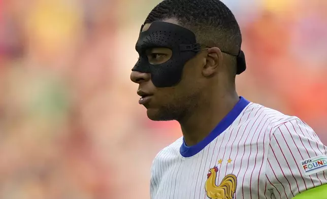 FILE - Kylian Mbappe of France wears a face mask during a round of sixteen match between France and Belgium at the Euro 2024 soccer tournament in Duesseldorf, Germany, on July 1, 2024. Kylian Mbappé has had more masks than goals at Euro 2024. Widely regarded as the heir to Lionel Messi and Cristiano Ronaldo as soccer's biggest icon, the France striker is struggling with his peripheral vision due to the protective face covering he has been fitted with since breaking his nose at the start of the European Championship.(AP Photo/Martin Meissner)