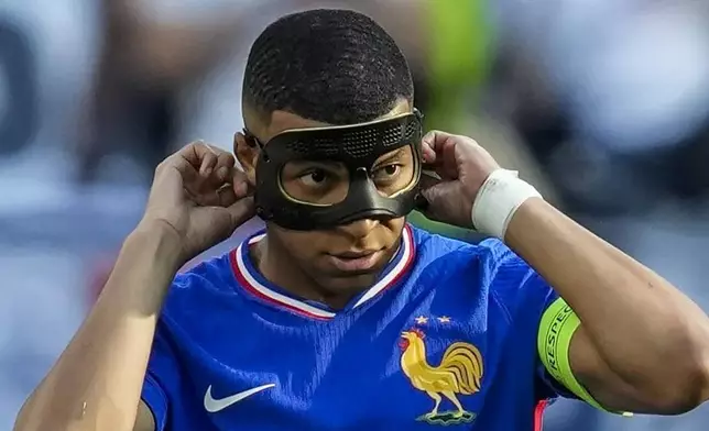 FILE - Kylian Mbappe of France adjusts his mask after scoring a penalty kick during a Group D match between the France and Poland at the Euro 2024 soccer tournament in Dortmund, Germany, on June 25, 2024. Kylian Mbappé has had more masks than goals at Euro 2024. Widely regarded as the heir to Lionel Messi and Cristiano Ronaldo as soccer's biggest icon, the France striker is struggling with his peripheral vision due to the protective face covering he has been fitted with since breaking his nose at the start of the European Championship. (AP Photo/Darko Vojinovic)
