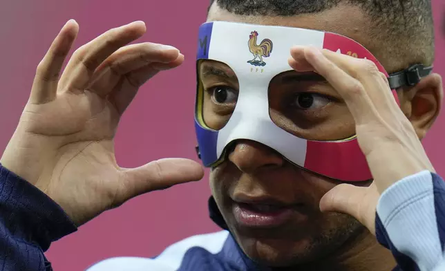 FILE - France's Kylian Mbappe adjusts his face mask during a training session in Leipzig, Germany, on June 20, 2024. Kylian Mbappé has had more masks than goals at Euro 2024. Widely regarded as the heir to Lionel Messi and Cristiano Ronaldo as soccer's biggest icon, the France striker is struggling with his peripheral vision due to the protective face covering he has been fitted with since breaking his nose at the start of the European Championship. (AP Photo/Hassan Ammar)