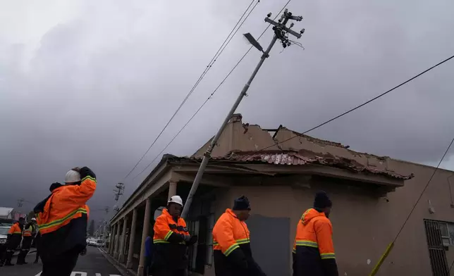 Rescue workers among damaged buildings in the Wynberg neighborhood of Cape Town, South Africa, Thursday, July 11, 2024. The area was hit overnight during strong winds that blew off roofs, destroyed parts of houses and other buildings, and brought down electricity poles. (AP Photo/Nardus Engelbrecht)