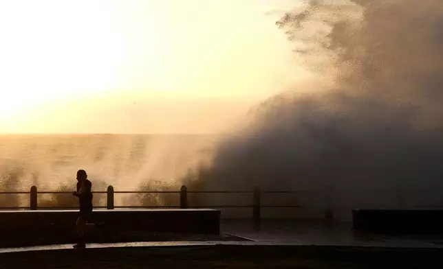 Waves break over Sea Point's promenade in Cape Town, South Africa, Monday, July 8, 2024. City authorities say nearly 1,000 homes in informal settlements around the city have been destroyed by gale-force winds, displacing around 4,000 people with multiple cold fronts expected until at least Friday. (AP Photo/Nardus Engelbrecht)
