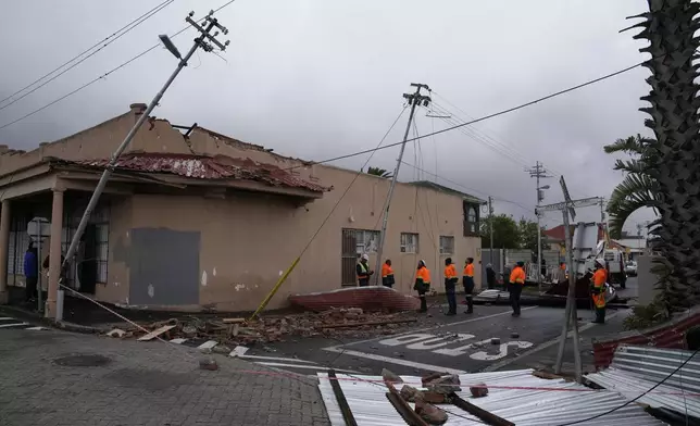 Rescue workers among damaged buildings in the Wynberg neighborhood of Cape Town, South Africa, Thursday, July 11, 2024. The area was hit overnight during strong winds that blew off roofs, destroyed parts of houses and other buildings, and brought down electricity poles. (AP Photo/Nardus Engelbrecht)