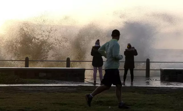 Waves break over Sea Point's promenade in Cape Town, South Africa, Monday, July 8, 2024. City authorities say nearly 1,000 homes in informal settlements around the city have been destroyed by gale-force winds, displacing around 4,000 people with multiple cold fronts expected until at least Friday. (AP Photo/Nardus Engelbrecht)