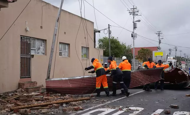 Rescue workers among damaged buildings in the Wynberg neighborhood of Cape Town, South Africa, Thursday, July 11, 2024. The area was hit overnight during strong winds that blew off roofs, destroyed parts of houses and other buildings, and brought down electricity poles. (AP Photo/Nardus Engelbrecht)
