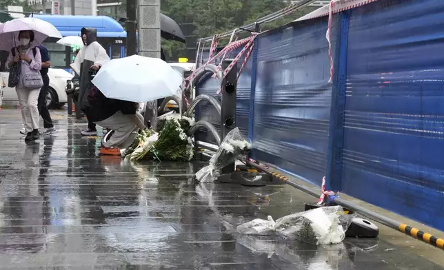 A woman places flowers at a car accident scene near Seoul City Hall in downtown Seoul, South Korea, Tuesday, July 2, 2024. A car hit several people Monday night, after reportedly going in the wrong direction and colliding with two other cars killing multiple people. The driver will be investigated on allegations of accidental homicide, police said Tuesday. (AP Photo/Ahn Young-joon)