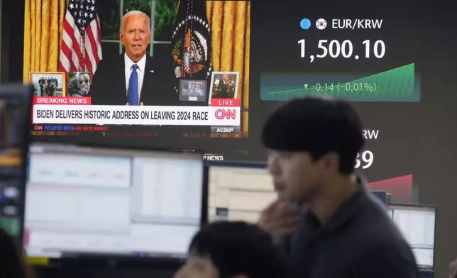 Currency traders watch monitors near a screen showing U.S. President Joe Biden at the foreign exchange dealing room of the KEB Hana Bank headquarters in Seoul, South Korea, Thursday, July 25, 2024. (AP Photo/Ahn Young-joon)