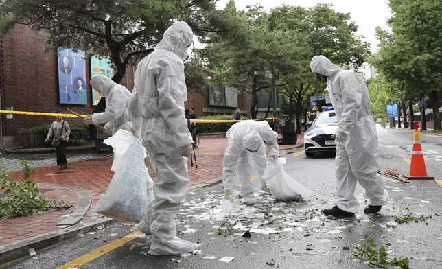 Officers wearing protective gear collect the trash from a balloon presumably sent by North Korea, Wednesday, July 24, 2024, in Seoul, South Korea. (Park Dong-joo/Yonhap via AP)