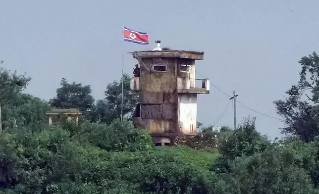 A North Korean soldier stands at the North's military guard post as a North Korean flag flutters in the wind, in this view from Paju, South Korea, Wednesday, July 24, 2024. North Korea flew more balloons likely carrying trash toward South Korea on Wednesday, Seoul officials said, days after South Korea boosted its frontline broadcasts of K-pop songs and propaganda messages across the rivals' heavily armed border. (AP Photo/Ahn Young-joon)