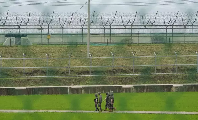 South Korean army soldiers pass by the barbed-wire fence in Paju, South Korea, near the border with North Korea, Friday, July 19, 2024. South Korea said Friday it has restarted blasting propaganda broadcasts into North Korea to retaliate against the North's latest round of trash-carrying balloon launches, a resumption of Cold War-style tactics that are raising animosities between the rivals. (AP Photo/Ahn Young-joon)