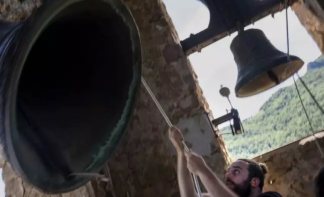 Guillem Pujolriu, a student of the Vall d'en Bas School of Bell Ringers, performs playing a bronze bell at the church bell tower of the12th-century Sant Romà church, at the tiny village of Joanetes, about two hours north of Barcelona, Spain, Saturday, July 29, 2024. A school set up to revive the manual ringing of church bells has graduated its first class of 18 students after learning their ringing skills. (AP Photo/Emilio Morenatti)