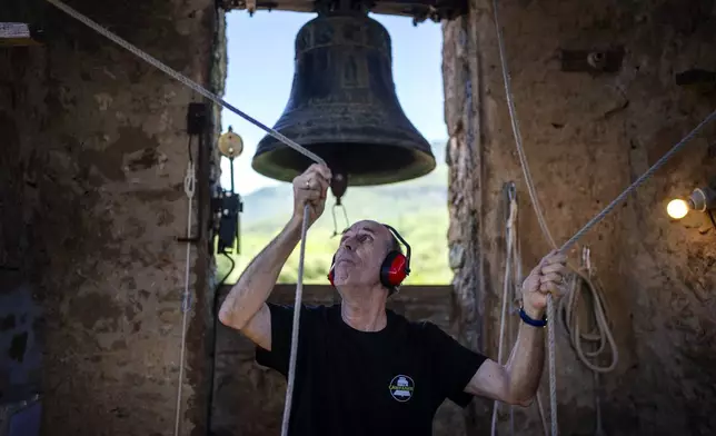 Josep-Maria Grosset, a student of the Vall d'en Bas School of Bell Ringers, performs playing two bronze bells at the church bell tower of the12th-century Sant Romà church, at the tiny village of Joanetes, about two hours north of Barcelona, Spain, Saturday, July 29, 2024. A school set up to revive the manual ringing of church bells has graduated its first class of 18 students after learning their ringing skills. (AP Photo/Emilio Morenatti)