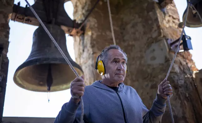 Xavier Masó, a student of the Vall d'en Bas School of Bell Ringers, performs playing two bronze bells at the church bell tower of the12th-century Sant Romà church, at the tiny village of Joanetes, about two hours north of Barcelona, Spain, Saturday, July 29, 2024. A school set up to revive the manual ringing of church bells has graduated its first class of 18 students after learning their ringing skills. (AP Photo/Emilio Morenatti)