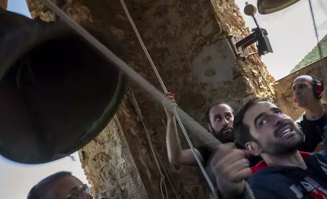 Students of the Vall d'en Bas School of Bell Ringers, perform playing all four bronze bells at the church bell tower of the12th-century Sant Romà church, at the tiny village of Joanetes, about two hours north of Barcelona, Spain, Saturday, July 29, 2024. A school set up to revive the manual ringing of church bells has graduated its first class of 18 students after learning their ringing skills. (AP Photo/Emilio Morenatti)