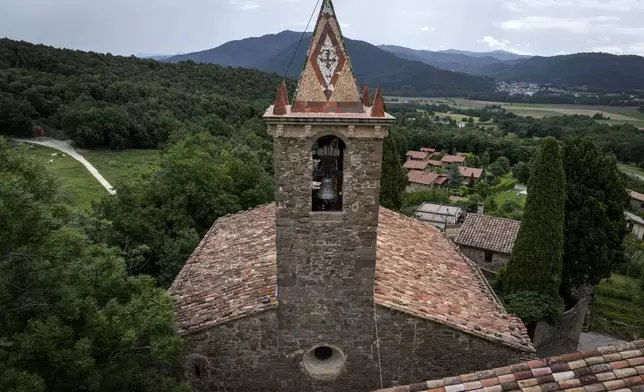 View of the bell tower of the12th-century Sant Romà church, where students of the Vall d'en Bas School of Bell Ringers perform playing bells, at the tiny village of Joanetes, about two hours north of Barcelona, Spain, Saturday, July 29, 2024. A school set up to revive the manual ringing of church bells has graduated its first class of 18 students after learning their ringing skills. (AP Photo/Emilio Morenatti)