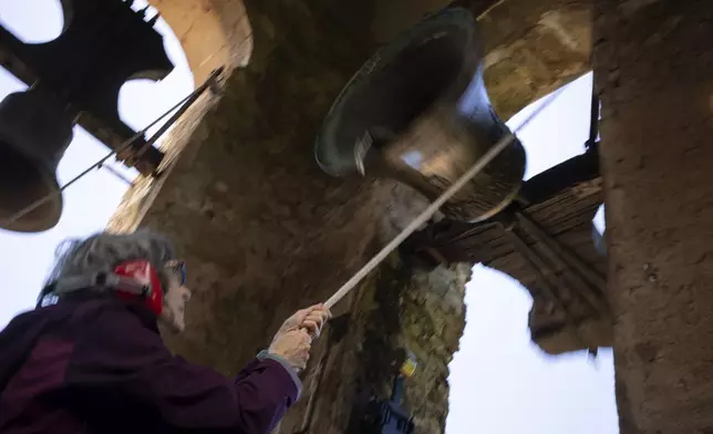 Roser Reixach, a student of the Vall d'en Bas School of Bell Ringers, performs playing a bronze bell at the church bell tower of the12th-century Sant Romà church, at the tiny village of Joanetes, about two hours north of Barcelona, Spain, Saturday, July 29, 2024. A school set up to revive the manual ringing of church bells has graduated its first class of 18 students after learning their ringing skills. (AP Photo/Emilio Morenatti)