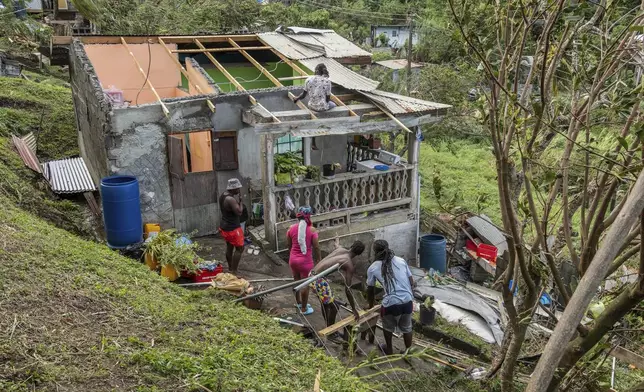 Family members begin to repair their home damaged in the passing of Hurricane Beryl, in Ottley Hall, St. Vincent and the Grenadines, Tuesday, July 2, 2024. (AP Photo/Lucanus Ollivierre)