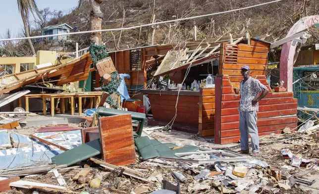 A man stands next to a business destroyed by Hurricane Beryl in Clifton, Union Island, St. Vincent and the Grenadines, Thursday, July 4, 2024. (AP Photo/Lucanus Ollivierre)