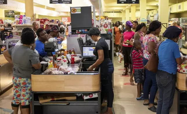 Costumers purchase groceries ahead of Hurricane Beryl in Arnos Vale, St. Vincent and the Grenadines, Sunday, June 30, 2024. (AP Photo/Lucanus Ollivierre)