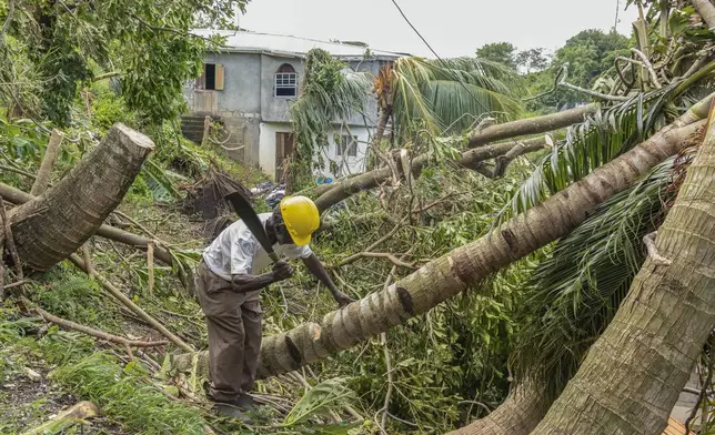 Pastor Winston Alleyne clears trees felled by Hurricane Beryl in Ottley Hall, St. Vincent and the Grenadines, Tuesday, July 2, 2024. (AP Photo/Lucanus Ollivierre)