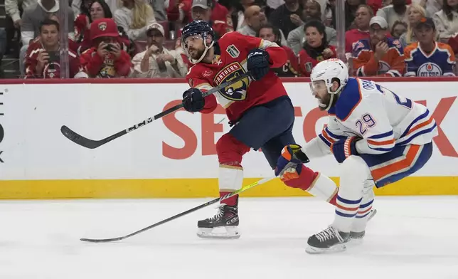 Florida Panthers center Sam Reinhart, left, aims the puck for a goal as Edmonton Oilers center Leon Draisaitl (29) attempts to defend during the second period of Game 7 of the NHL hockey Stanley Cup Final, Monday, June 24, 2024, in Sunrise, Fla. (AP Photo/Wilfredo Lee)