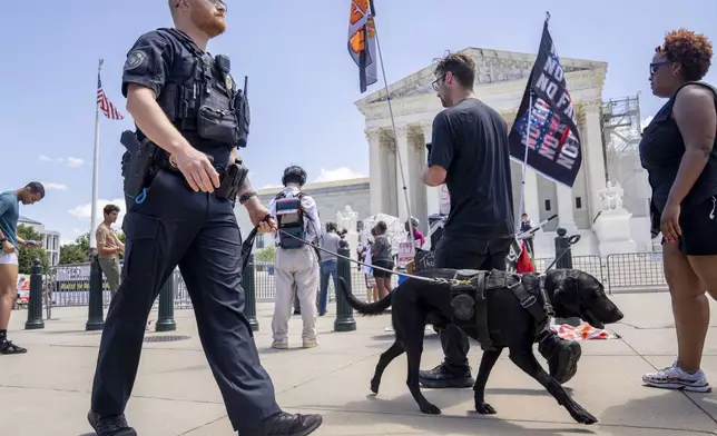 A U.S. Capitol Police officer and K-9 patrol pass protesters by the Supreme Court, Monday, July 1, 2024, after court decisions were announced in Washington. (AP Photo/Jacquelyn Martin)