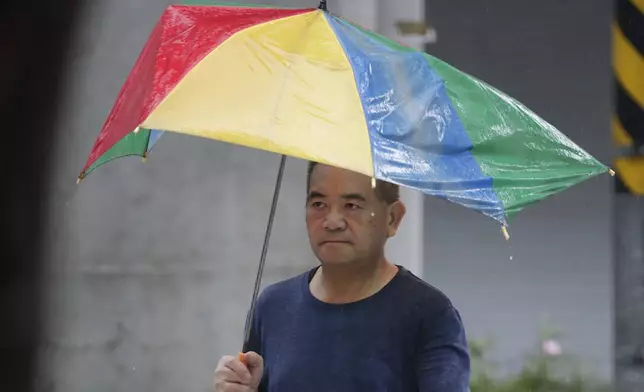 A man holds a ruined umbrella after struggling against gusts of wind generated by Typhoon Gaemi in Taipei, Taiwan, Wednesday, July 24, 2024. (AP Photo/Chiang Ying-ying)