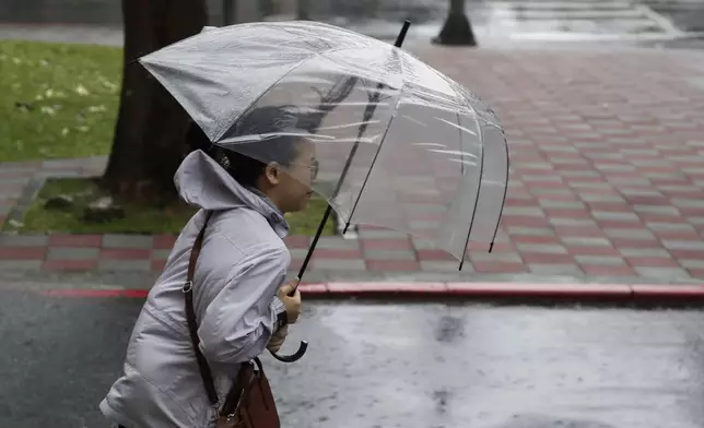 A woman struggles with her umbrella against gusts of wind generated by Typhoon Gaemi in Taipei, Taiwan, Wednesday, July 24, 2024. (AP Photo/Chiang Ying-ying)