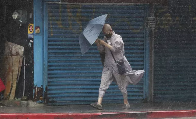 A Buddhist nun struggles with her umbrella against gusts of wind generated by Typhoon Gaemi in Taipei, Taiwan, Wednesday, July 24, 2024. (AP Photo/Chiang Ying-ying)