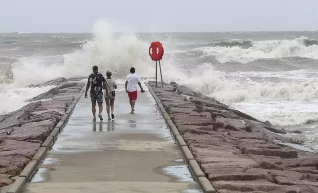 People watch waves crash into the 37th Street rock groin in Galveston, Texas on Sunday, July 7, 2024, as Tropical Storm Beryl churns toward the Texas Coast. (Jennifer Reynolds/The Galveston County Daily News via AP)