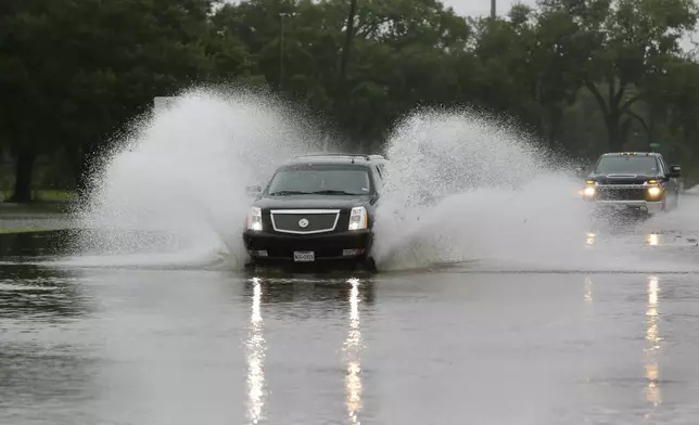 Motorists drive through flood waters on Reading Rd. during a lull in the wind and rain as Tropical Storm Beryl passes Monday, July 8, 2024, in Rosenburg, Texas. Hurricane Beryl has been downgraded to a tropical storm after sweeping into Texas as a Category 1 storm with heavy rains and powerful winds. (AP Photo/Michael Wyke)