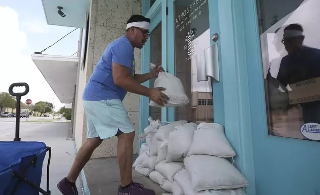 Richard Alcazar stacks sandbags in front of the door at Atmosphere The Salon &amp; Beyond in Galveston, Texas, Sunday, July 7, 2024, as Tropical Storm Beryl heads toward the Texas coast. Alcazar, a barber at the salon, prepared the doors for any possible flooding from the storm. ( Jennifer Reynolds/The Galveston County Daily News via AP)