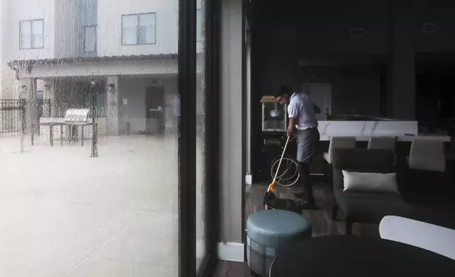 Andrew Parada, an employee at Residence Inn mops up the floor as water keeps leaking in during Tropical Storm Beryl wanes on Monday, July 8, 2024, Galveston, Texas. (Elizabeth Conley/Houston Chronicle via AP)